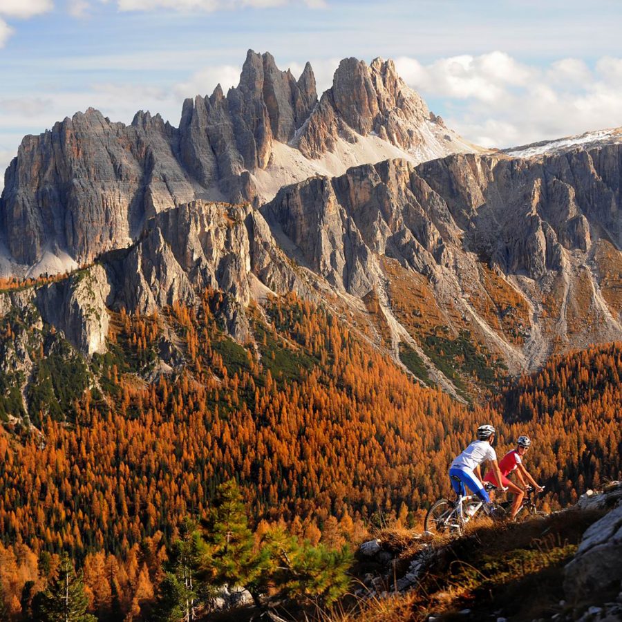 The Dolomites’ folds of grey stone slope down into a colourful forest in the autumn, where one can hike if staying at Cortina d’Ampezzo. 
